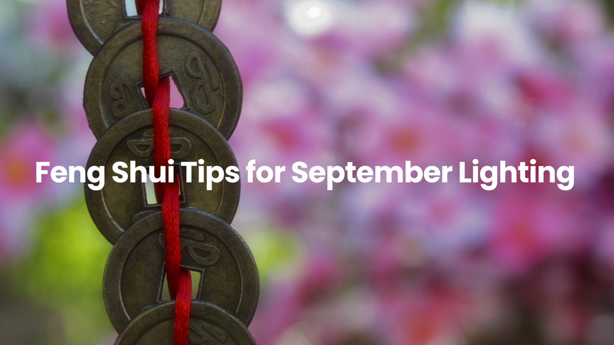 Traditional Feng Shui coins tied with red string against a soft floral background, symbolizing balance, prosperity, and harmonious lighting inspiration for September.