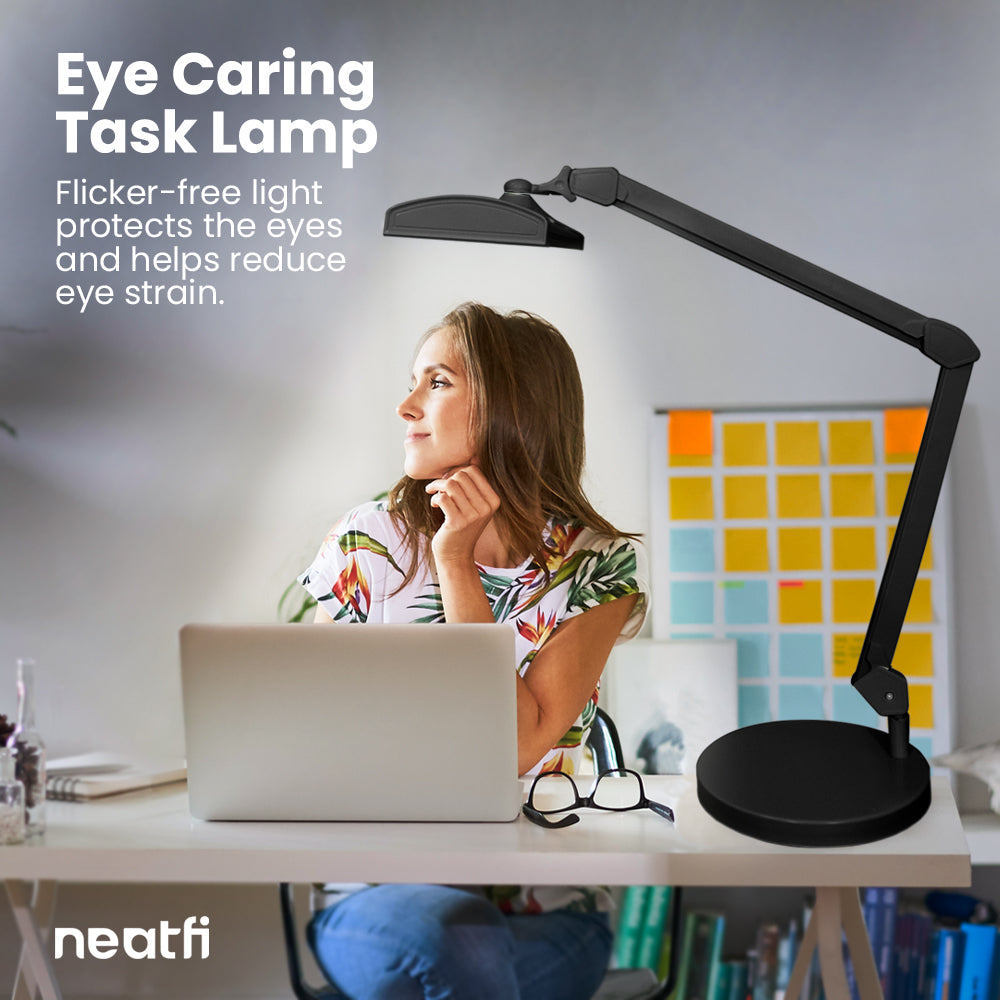 Eye-caring 26-inch LED black desk lamp with base providing flicker-free light over a home office desk, helping reduce eye strain while working on a laptop.