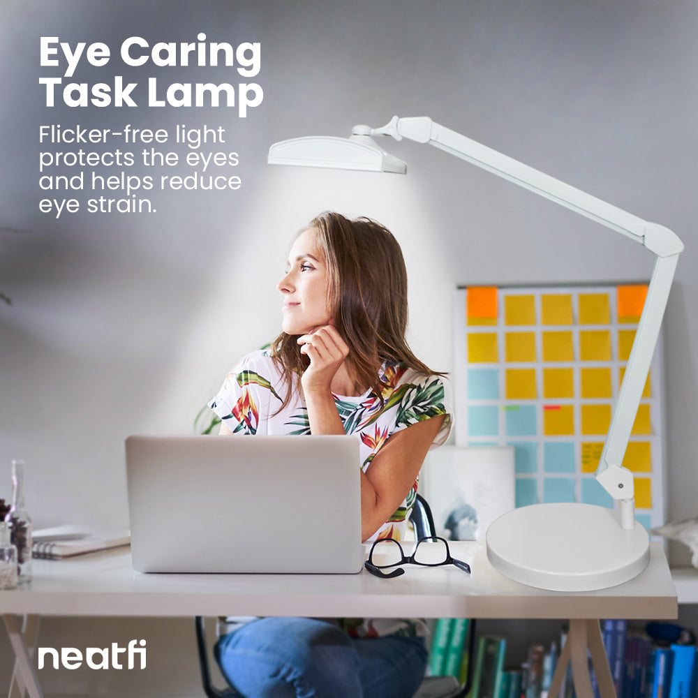 Eye-caring 26-inch LED white desk lamp with base providing flicker-free light over a home office desk, helping reduce eye strain while working on a laptop.