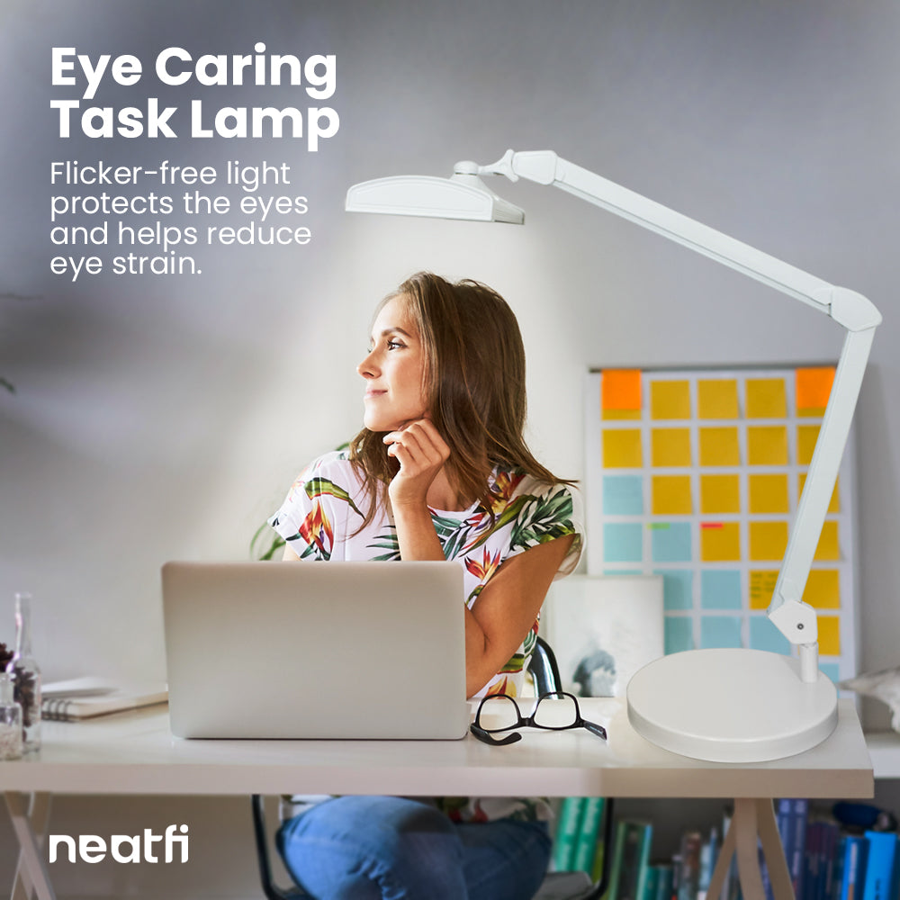 Eye-caring 26-inch LED white desk lamp with base providing flicker-free light over a home office desk, helping reduce eye strain while working on a laptop.
