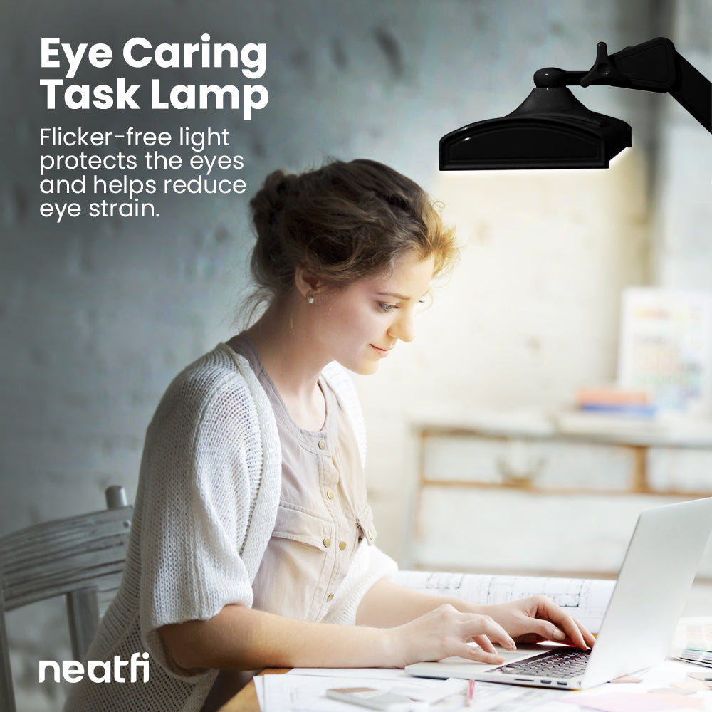 Eye-caring 26-inch black LED desk lamp with clamp providing flicker-free lighting over a desk, helping reduce eye strain while working on a laptop.