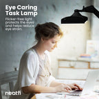 Eye-caring 26-inch black LED desk lamp with clamp providing flicker-free lighting over a desk, helping reduce eye strain while working on a laptop.